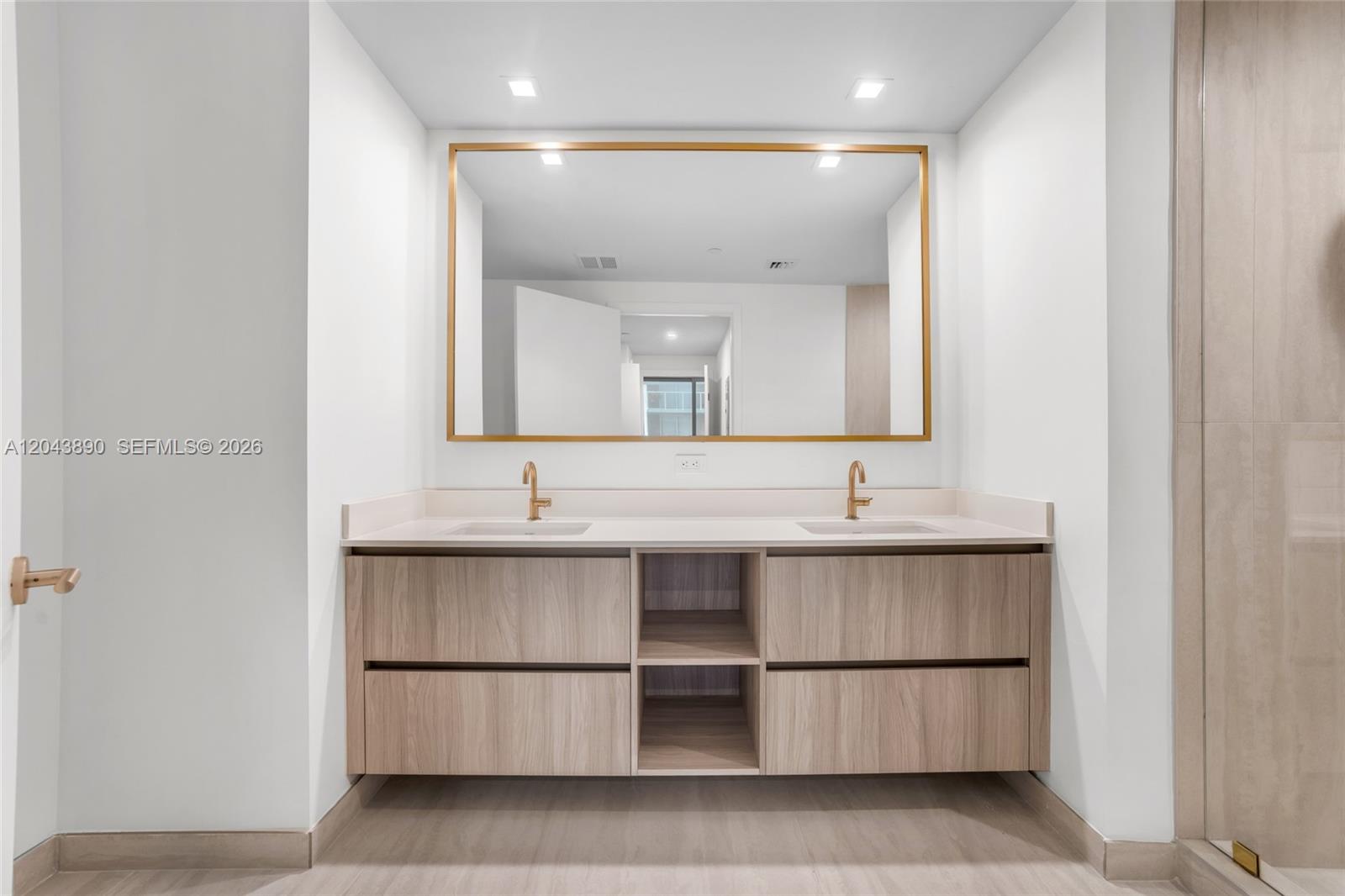 A modern bathroom features a double vanity with light wood cabinets and gold fixtures — 77 SE 5th Street # 1708, Miami FL 33131, MIAMI, FL