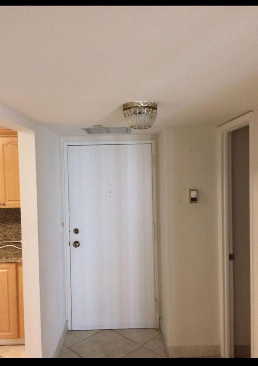 A white front door in an entryway with tile flooring and a decorative ceiling light — 1865 Brickell Avenue # A707, Miami FL 33129, MIAMI, FL