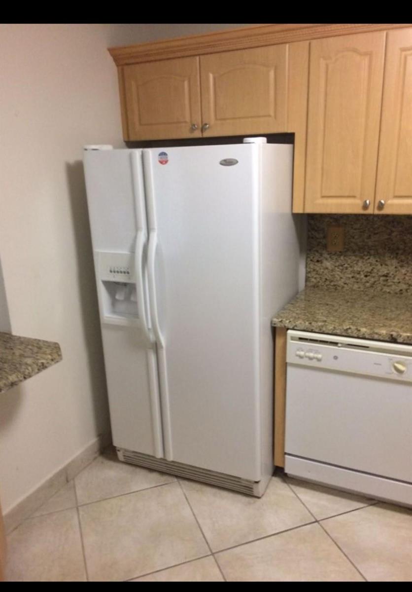 A white side-by-side refrigerator stands next to a dishwasher and granite countertops in a kitchen — 1865 Brickell Avenue # A707, Miami FL 33129, MIAMI, FL