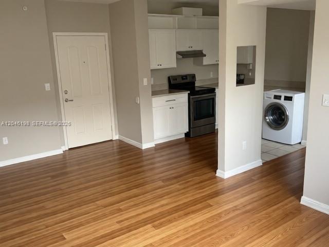 A kitchen with white cabinets and a stainless steel stove sits beside a laundry area — 5091 NW 7th St # 0, Miami FL 33126, MIAMI, FL