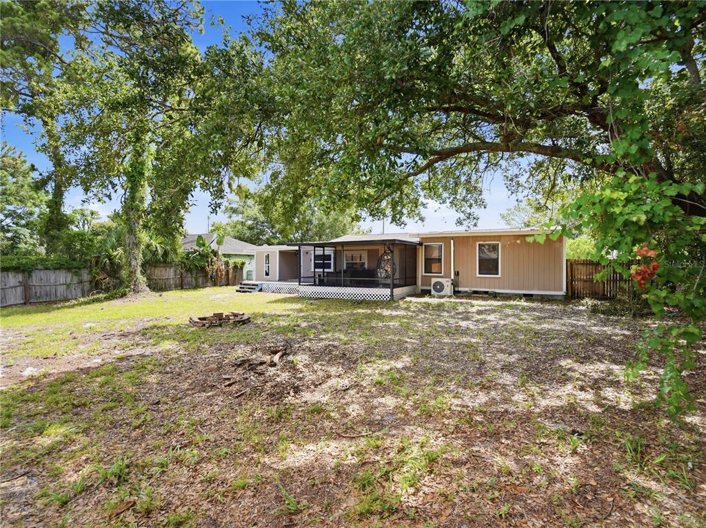 A screened-in patio features a hanging egg chair, wicker sofa, and views of the yard — 6592 EMIL AVENUE, COCOA, FL