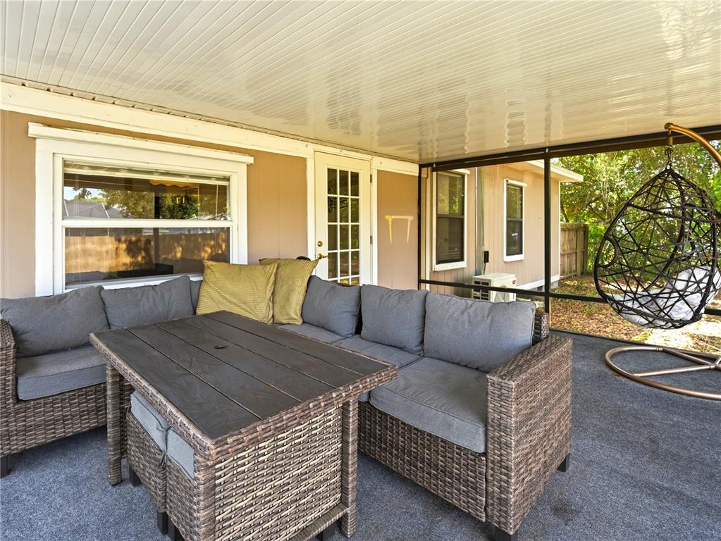 A screened-in porch features gray wicker sectional seating, a dining table, and a hanging chair — 6592 EMIL AVENUE, COCOA, FL