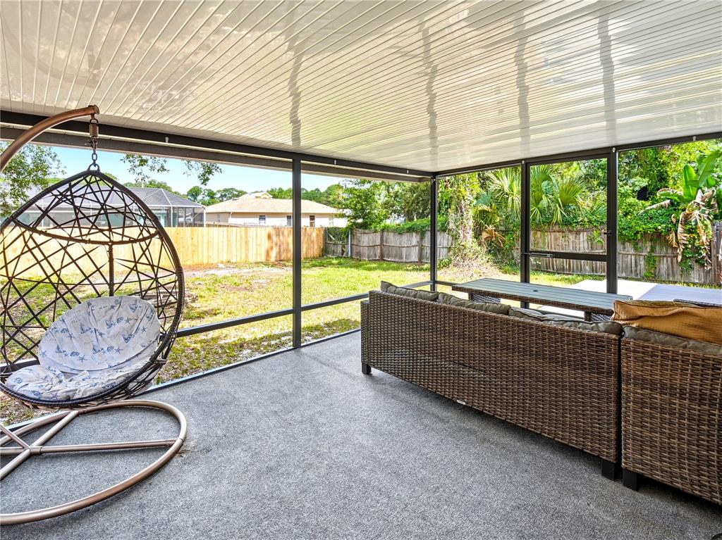 A living room features a grey sectional sofa, wood-look flooring, a ceiling fan, and a television — 6592 EMIL AVENUE, COCOA, FL