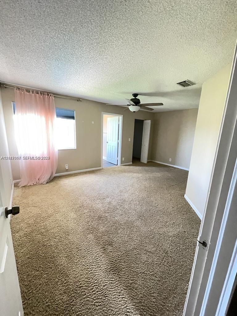 A carpeted bedroom features a ceiling fan, a window with pink curtains, and two doorways — 558 Stonemont Dr # 558, Weston FL 33326, WESTON, FL