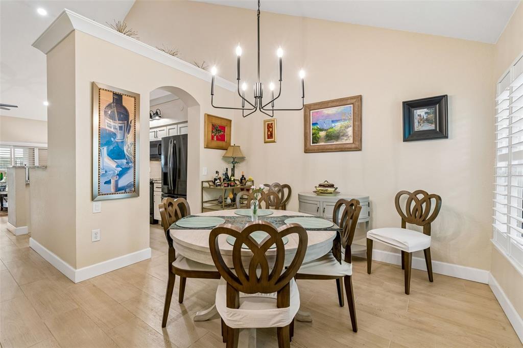 A dining area features a round table with chairs, a chandelier, and framed wall art — 3638 TRAFALGAR WAY UNIT 102, PALM HARBOR, FL