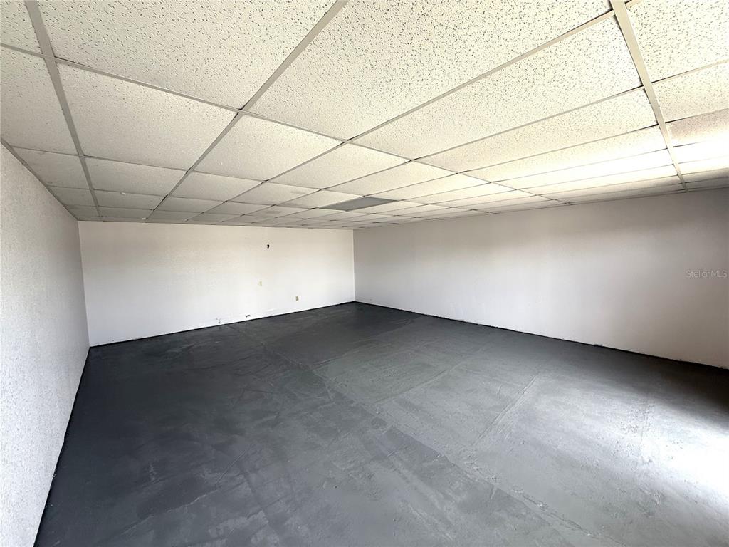 An empty room features white walls, a drop ceiling, and a painted gray concrete floor — 1401 SW MARTIN LUTHER KING JR STREET, ARCADIA, FL