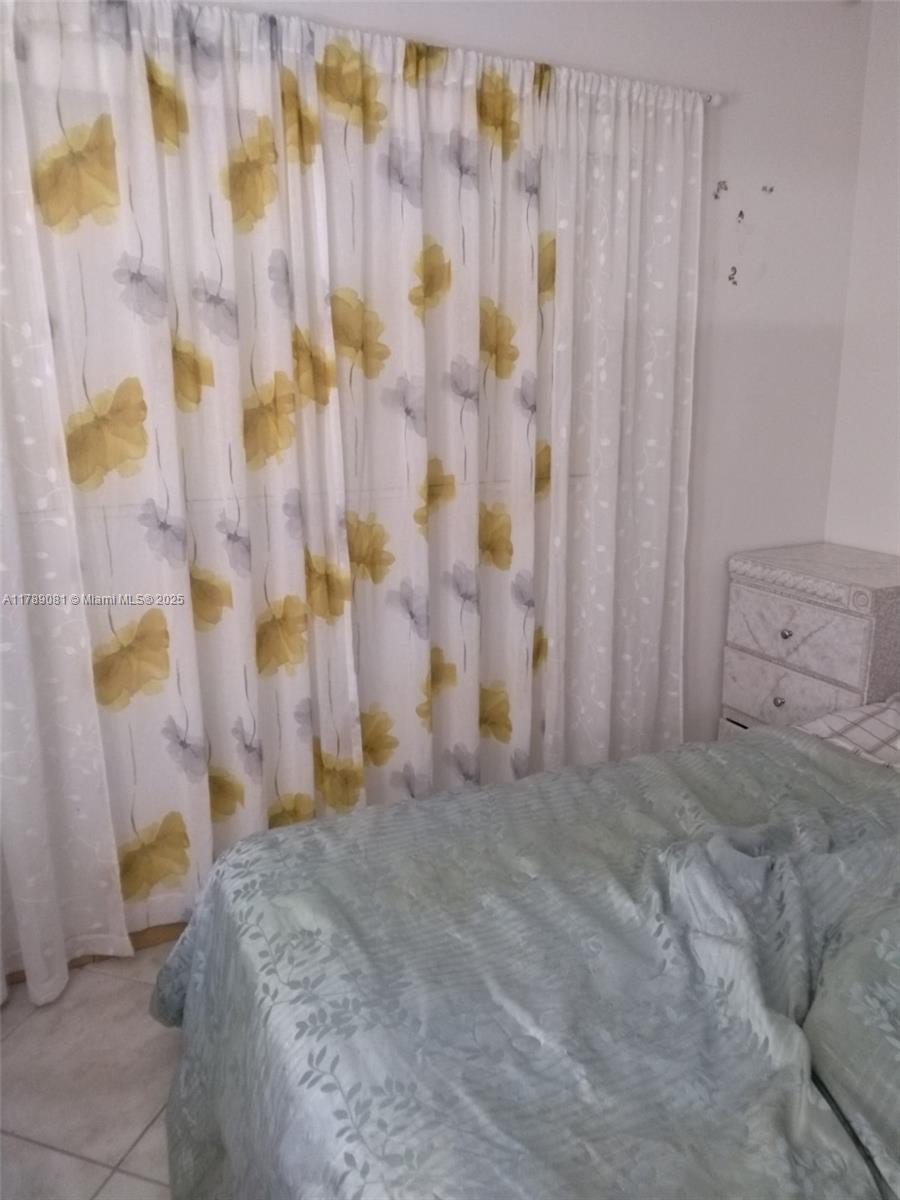 A bedroom features floral curtains, a light green bedspread, and a small white nightstand — 6510 Winfield Blvd # 103, Margate FL 33063, MARGATE, FL