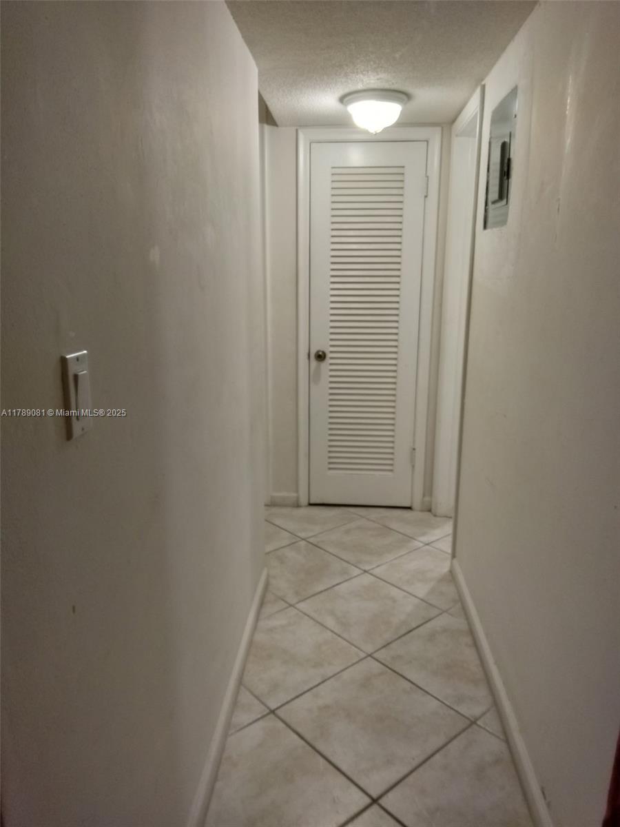 A narrow hallway features white walls, tiled flooring, and a louvered door at the end — 6510 Winfield Blvd # 103, Margate FL 33063, MARGATE, FL