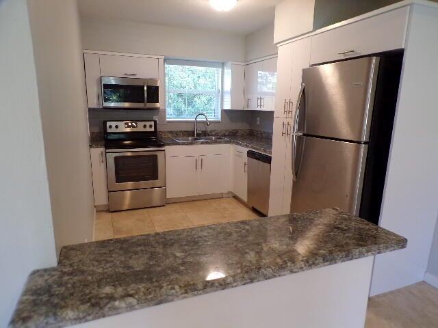 A kitchen features white cabinets, stainless steel appliances, and a granite-topped breakfast bar — 2210 NE 36th Street, Lighthouse Point FL 33064, LIGHTHOUSE POINT, FL