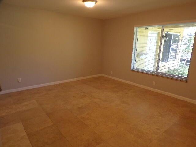 An empty room features light-colored walls, a large window with blinds, and tiled flooring — 2210 NE 36th Street, Lighthouse Point FL 33064, LIGHTHOUSE POINT, FL