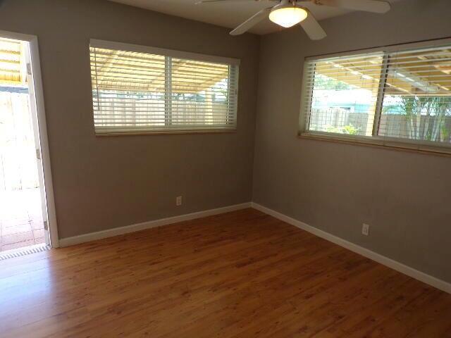 An empty room with wood-look flooring, two windows with blinds, and a ceiling fan — 2210 NE 36th Street, Lighthouse Point FL 33064, LIGHTHOUSE POINT, FL
