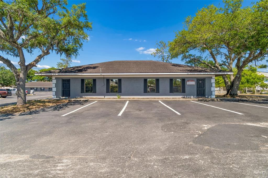 A single-story gray commercial building with a parking lot in the foreground — 7517 LITTLE ROAD, NEW PORT RICHEY, FL