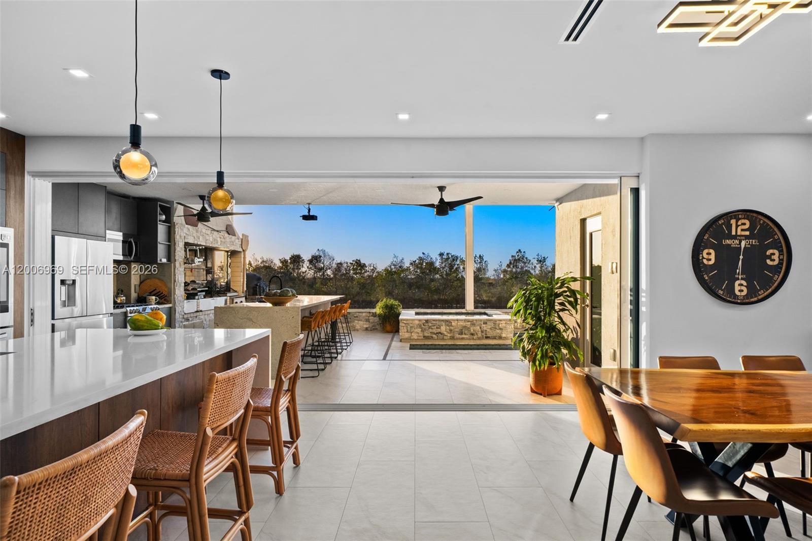 An open-concept kitchen and dining area leads to a covered patio with an outdoor kitchen — 1828 Aspen Ln, Weston FL 33327, WESTON, FL