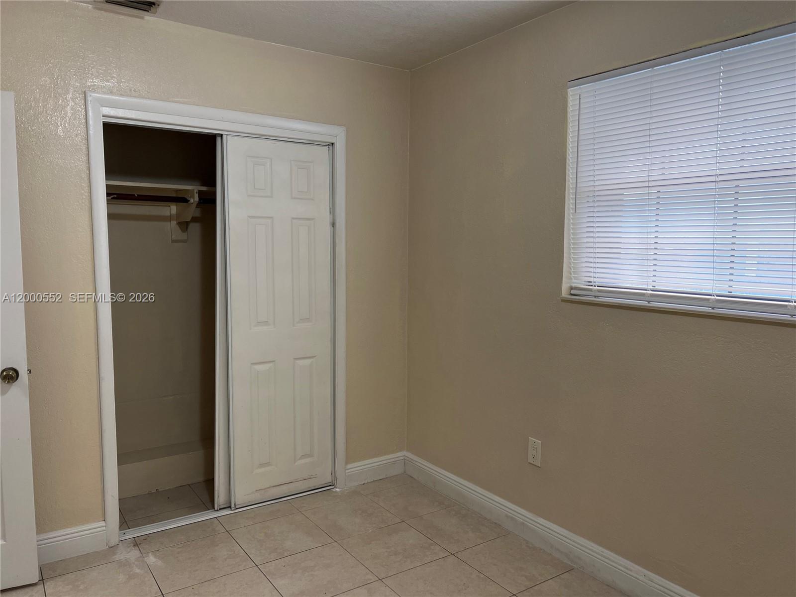 A bedroom features beige walls, tiled flooring, a sliding closet door, and a window with blinds — 931 NW 34th Way, Lauderhill FL 33311, LAUDERHILL, FL