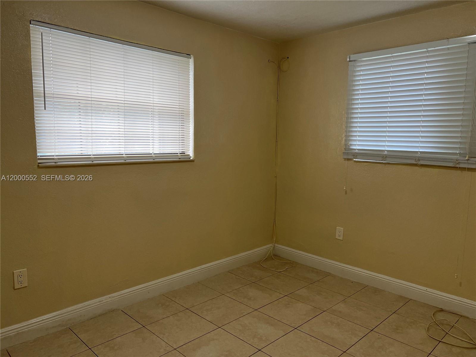 An empty room features beige walls, tiled flooring, and two windows with white blinds — 931 NW 34th Way, Lauderhill FL 33311, LAUDERHILL, FL