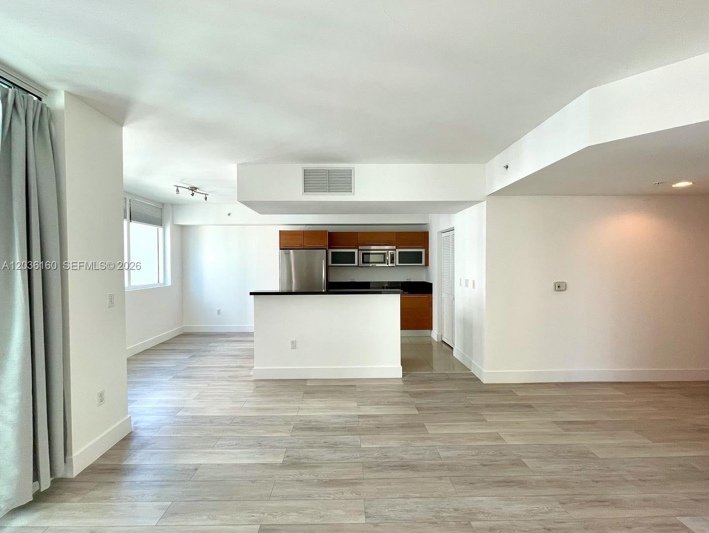An open-concept living area features light wood-look flooring and a kitchen with dark countertops — 253 NE 2nd St # 2108, Miami FL 33132, MIAMI, FL