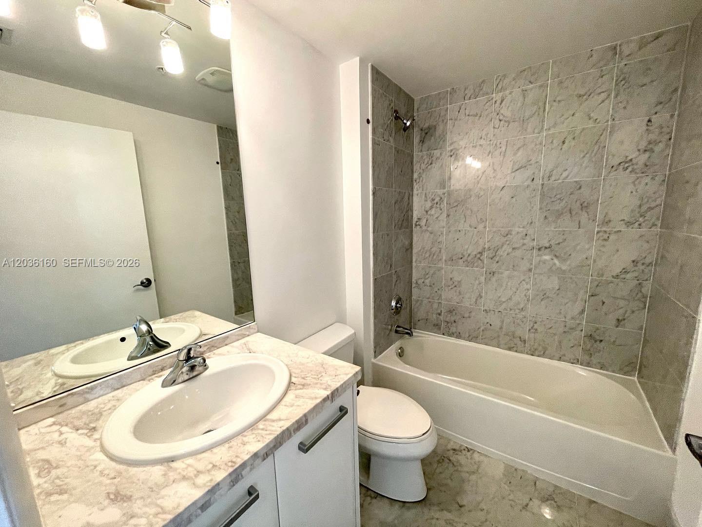 A bathroom features a marble-topped vanity, a white toilet, and a tiled shower-tub combination — 253 NE 2nd St # 2108, Miami FL 33132, MIAMI, FL
