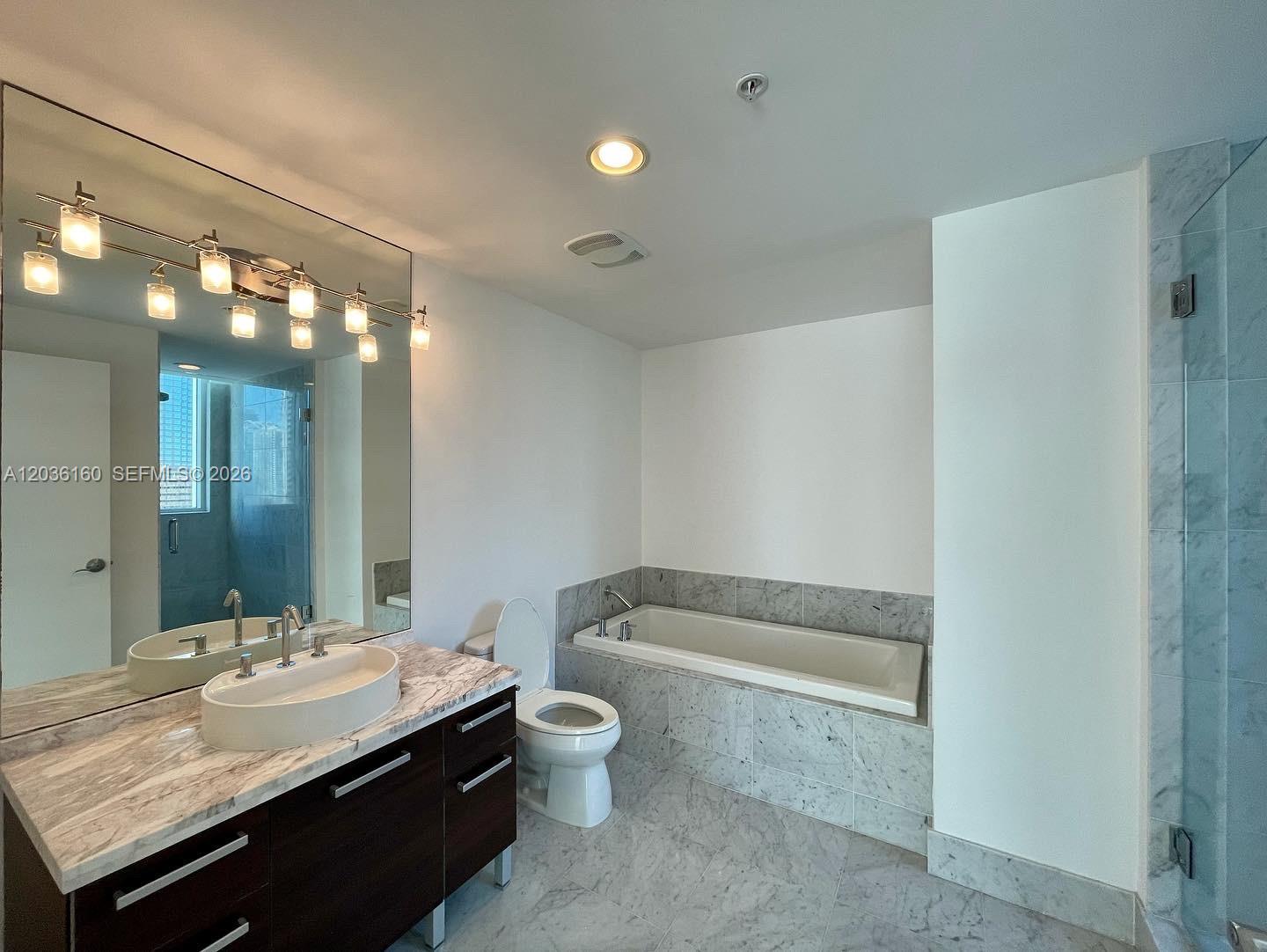 A modern bathroom features a marble-topped vanity, a soaking tub, and a glass-enclosed shower — 253 NE 2nd St # 2108, Miami FL 33132, MIAMI, FL