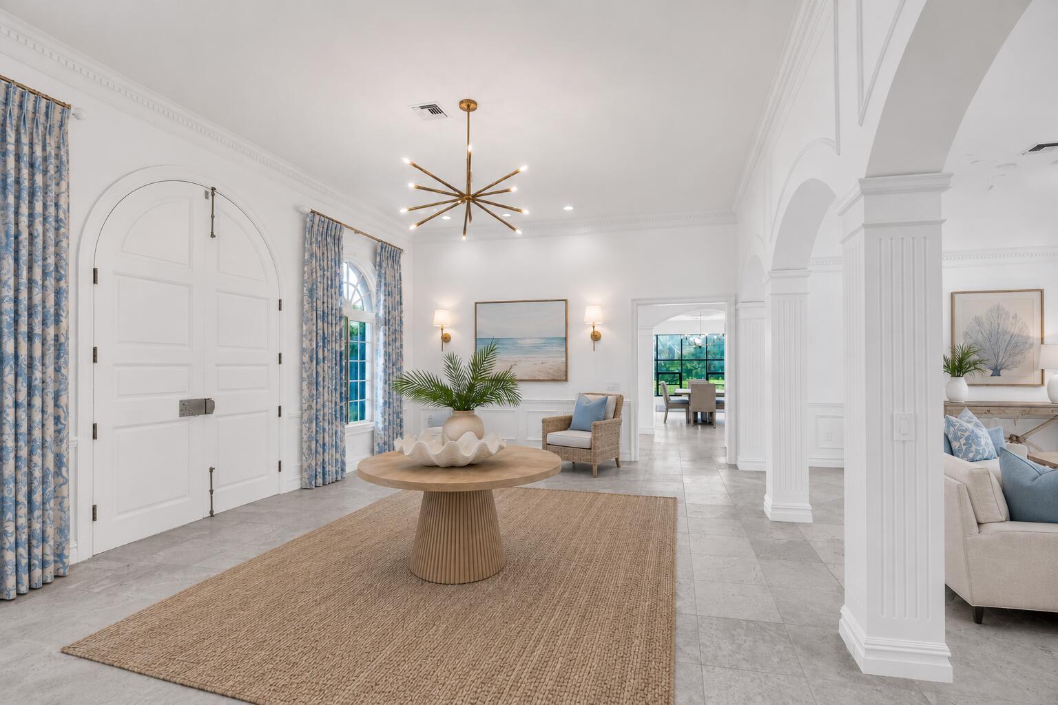 A bright foyer features a round wooden table, a large rug, and arched architectural details — VERO BEACH, FL