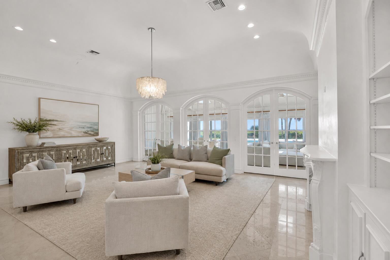 A bright living room features arched glass doors, a chandelier, and neutral furniture on tile — VERO BEACH, FL