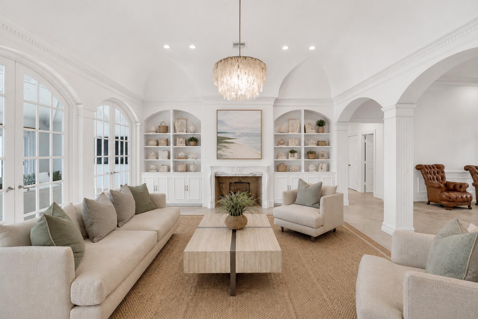 A bright living room features a fireplace, built-in shelving, arched windows, and neutral furniture — VERO BEACH, FL
