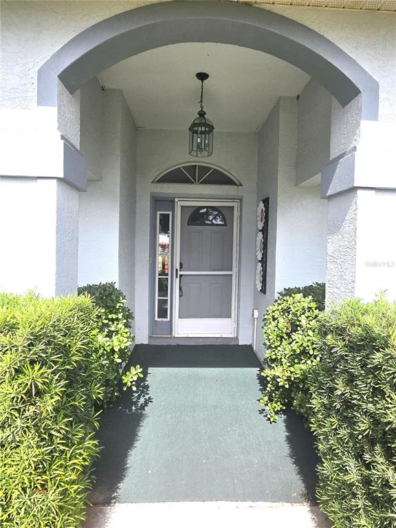 A covered entryway features a gray front door with a sidelight and a hanging lantern — 3434 NW 50TH COURT, OCALA, FL