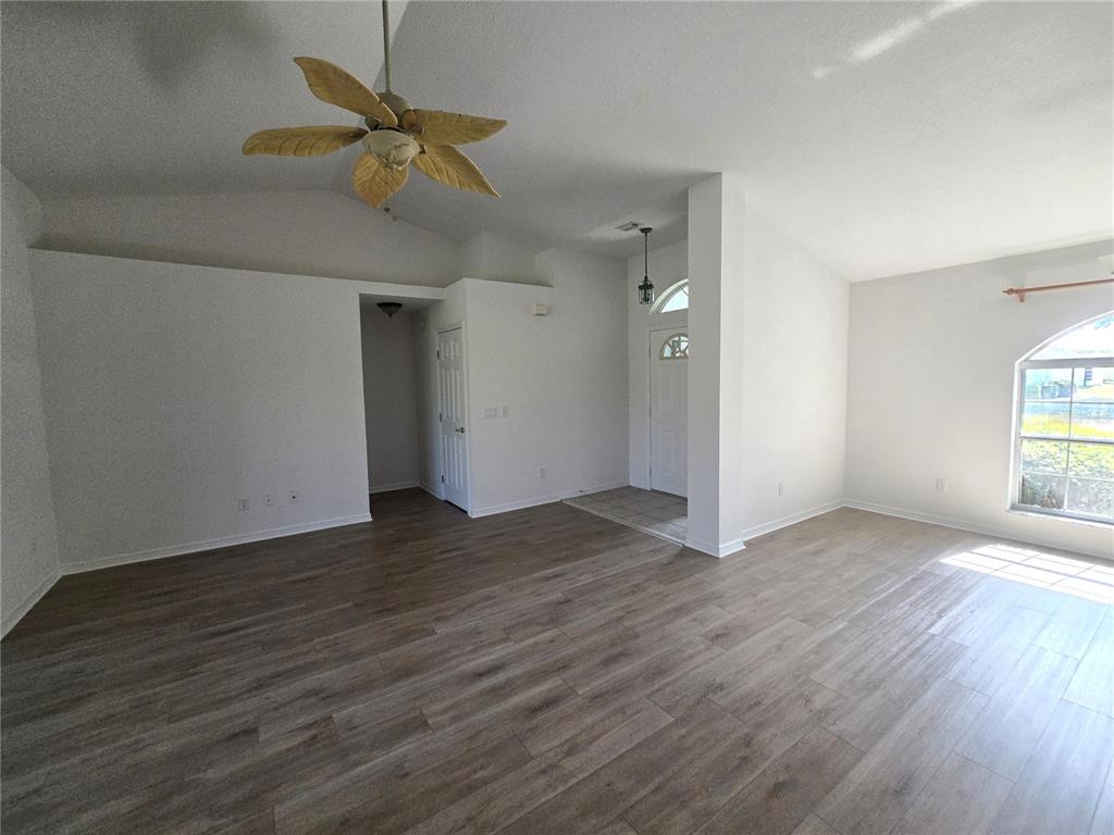 A living room features vaulted ceilings, wood-look flooring, a ceiling fan, and an entryway — 3434 NW 50TH COURT, OCALA, FL