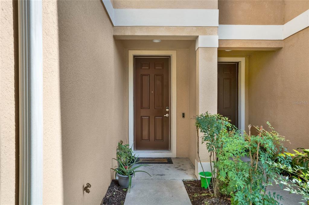 A brown front door is set within a recessed entryway with beige stucco walls — 1214 CHELSEA DRIVE, DAVENPORT, FL