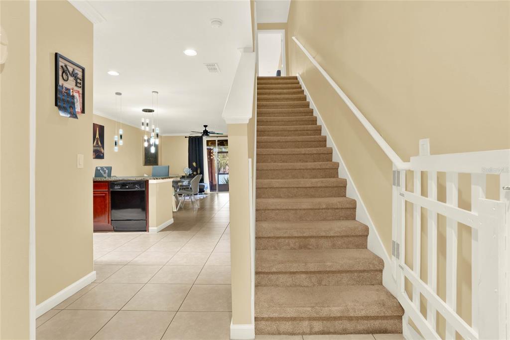 A carpeted staircase leads upstairs next to a tiled kitchen and dining area — 1214 CHELSEA DRIVE, DAVENPORT, FL