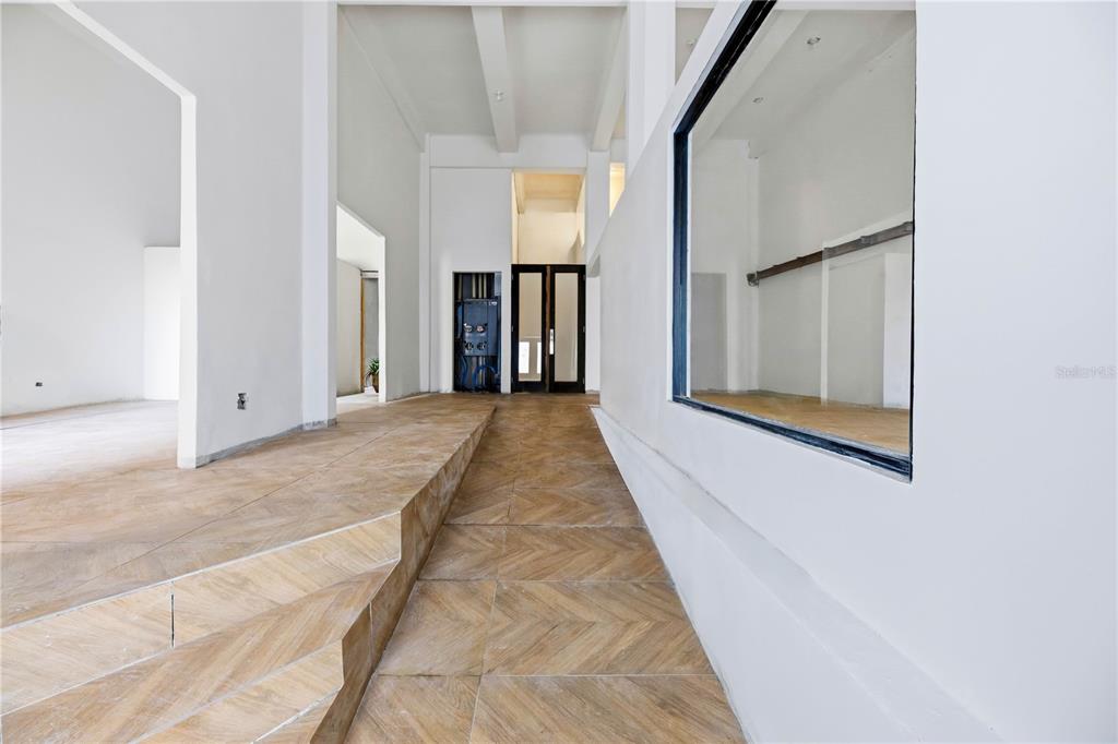A bright, minimalist hallway features a raised platform, wood-look tile flooring, and a large window — 205 TETUAN STREET, SAN JUAN, PR