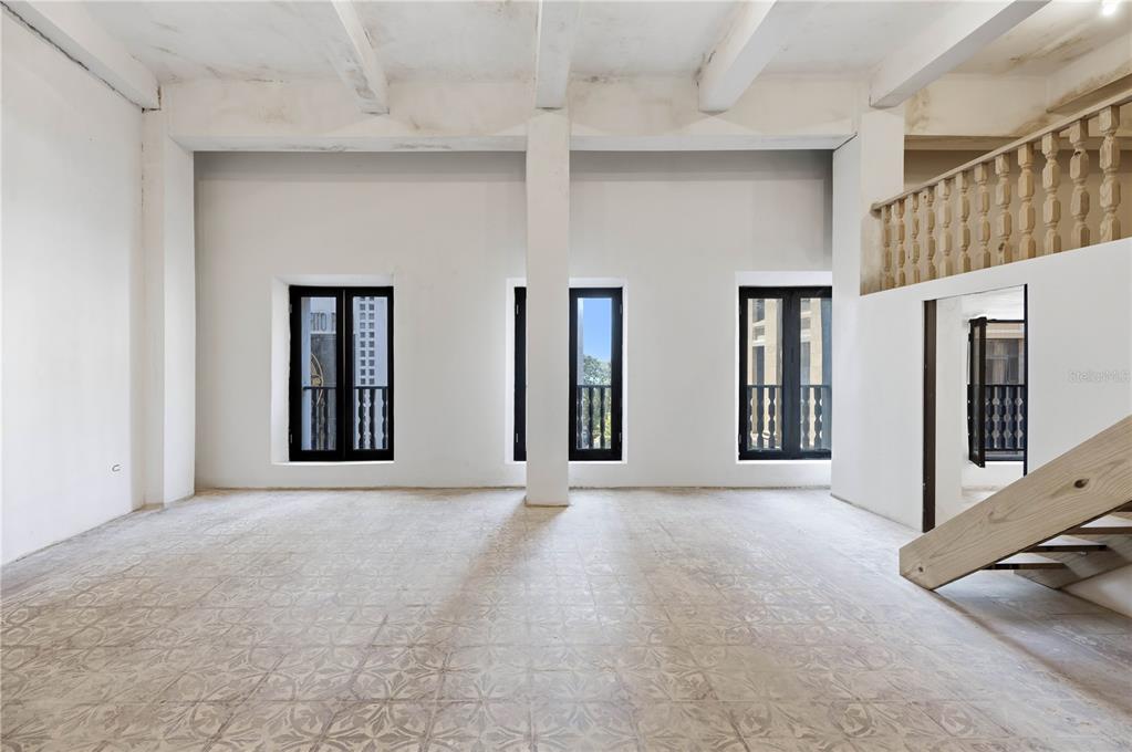 An empty room with white walls, patterned tile floors, exposed ceiling beams, and three windows — 205 TETUAN STREET, SAN JUAN, PR