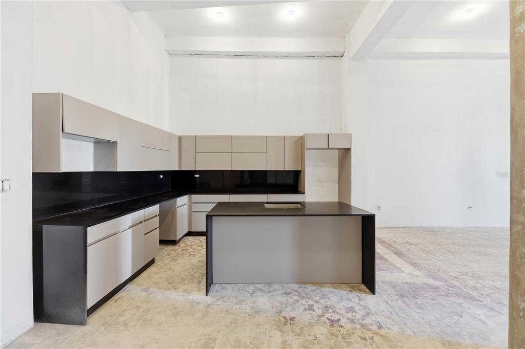 A modern kitchen features light gray cabinets, black countertops, and a matching central island — 205 TETUAN STREET, SAN JUAN, PR