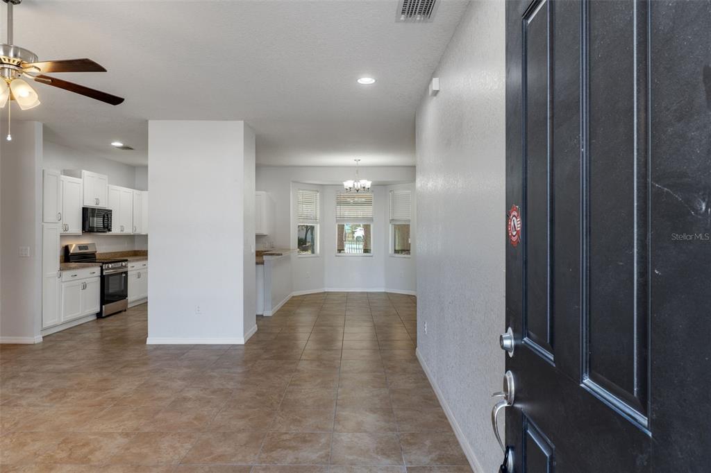 An open-concept kitchen and dining area with tile flooring and white cabinetry — 13124 SNOWY PLOVER AVENUE, WEEKI WACHEE, FL
