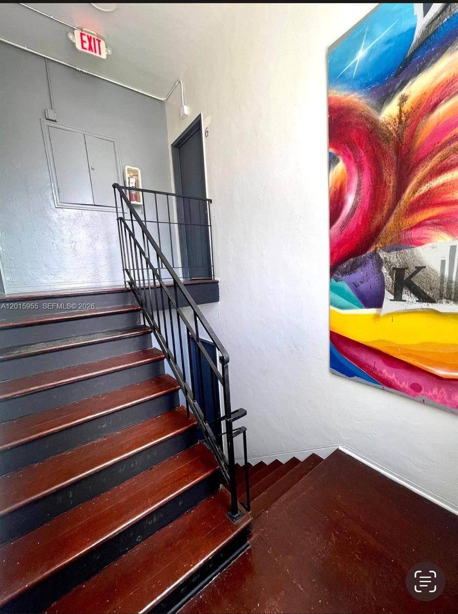 A staircase with dark wood treads and a black metal railing leads to a landing — MIAMI BEACH, FL