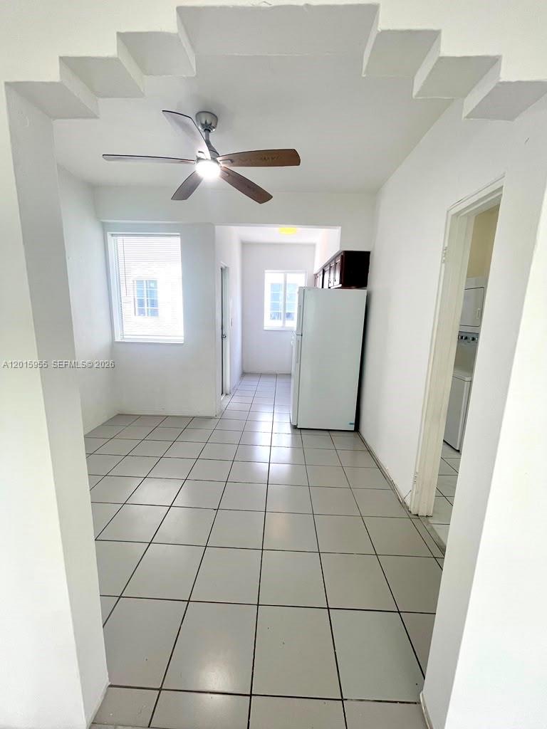 A tiled kitchen area features a white refrigerator, a ceiling fan, and white walls — MIAMI BEACH, FL