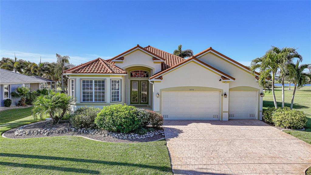 A single-story house with a tile roof, two-car garage, and a landscaped front yard — 3775 TRIPOLI BOULEVARD, PUNTA GORDA, FL
