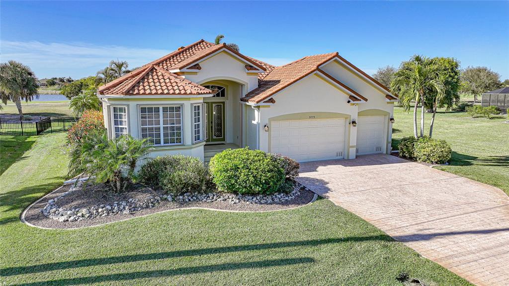 A single-story house with a tiled roof, a two-car garage, and a landscaped front yard — 3775 TRIPOLI BOULEVARD, PUNTA GORDA, FL