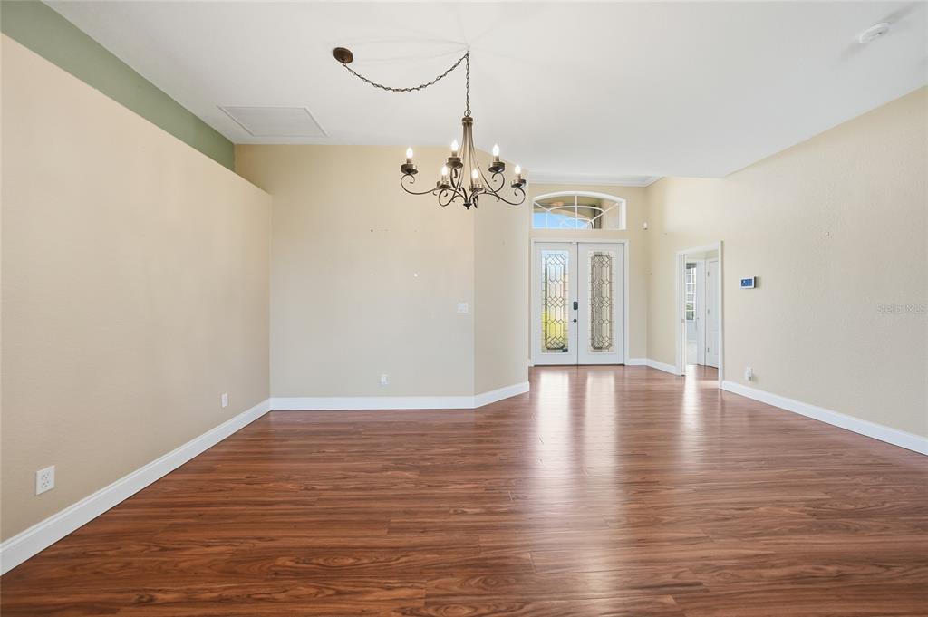 An empty room with wood-look flooring, beige walls, and a decorative chandelier — 3775 TRIPOLI BOULEVARD, PUNTA GORDA, FL