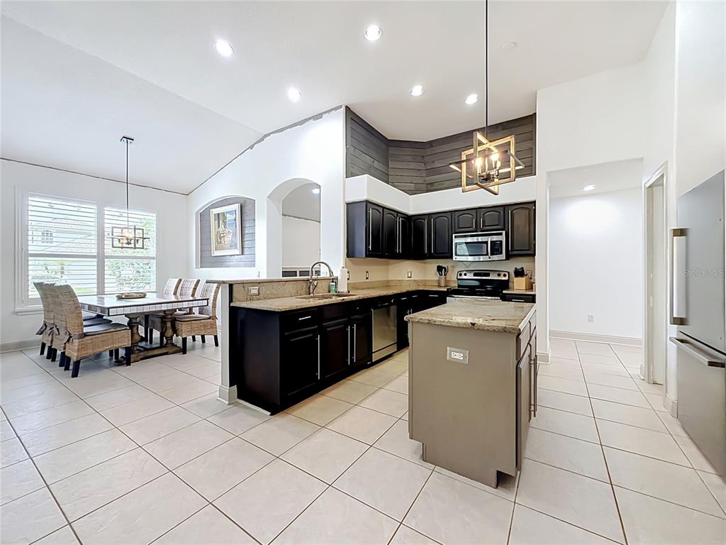 A kitchen with dark cabinets, a central island, and an adjacent dining area with tile flooring — 5846 BENT GRASS DRIVE, VALRICO, FL