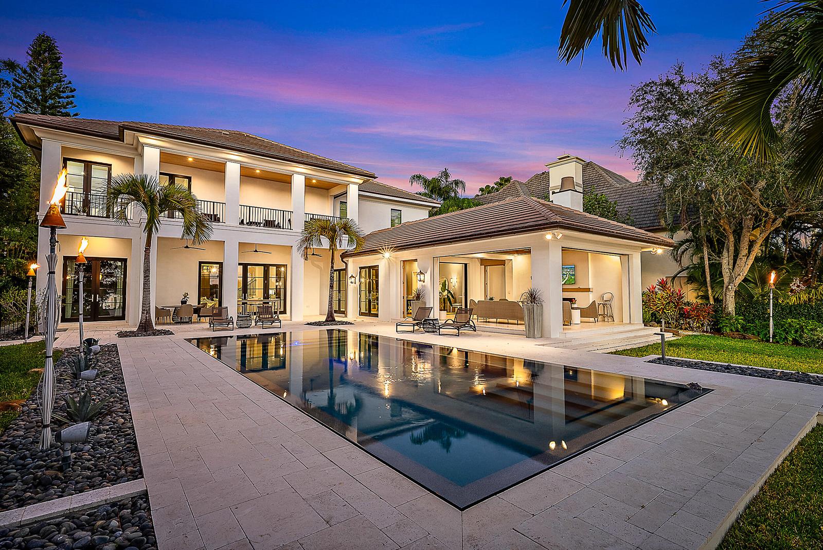 A two-story house with a pool, patio, and open-air living space at dusk — 19651 Riverside Drive, Jupiter FL 33469, JUPITER, FL