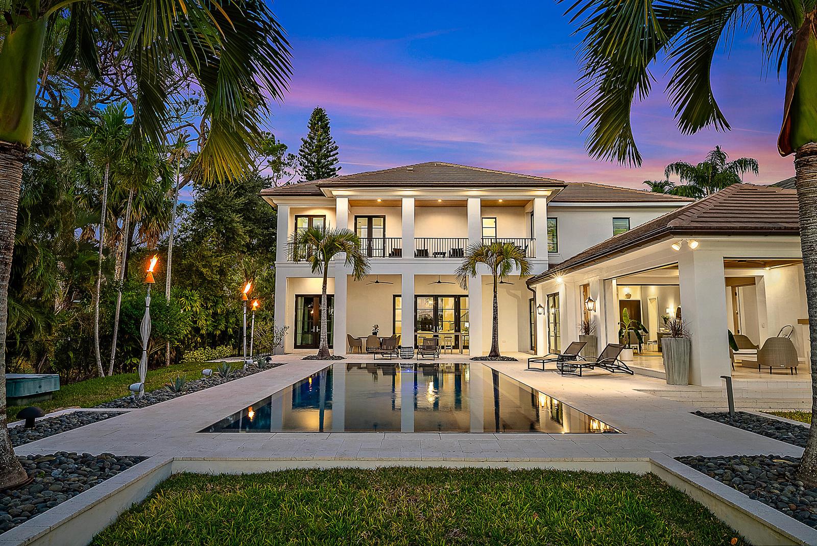 A two-story house with a pool, patio, and palm trees at dusk — 19651 Riverside Drive, Jupiter FL 33469, JUPITER, FL