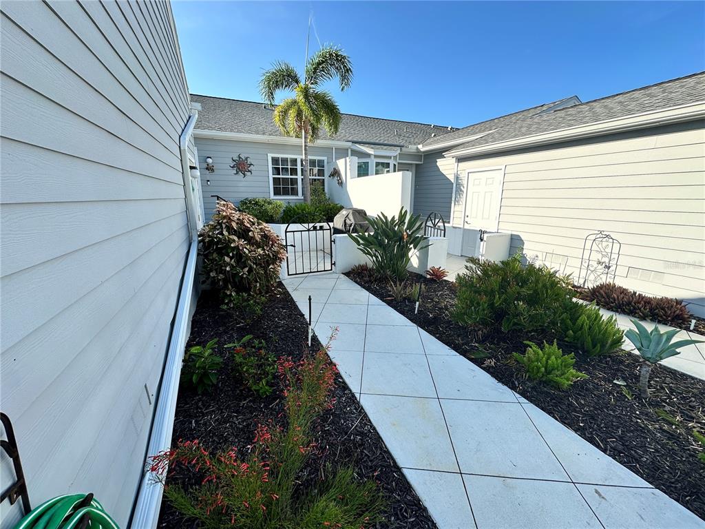 A concrete walkway leads to a gated entrance between two sections of a house — 1233 SPOONBILL LANDINGS CIRCLE UNIT NA, BRADENTON, FL