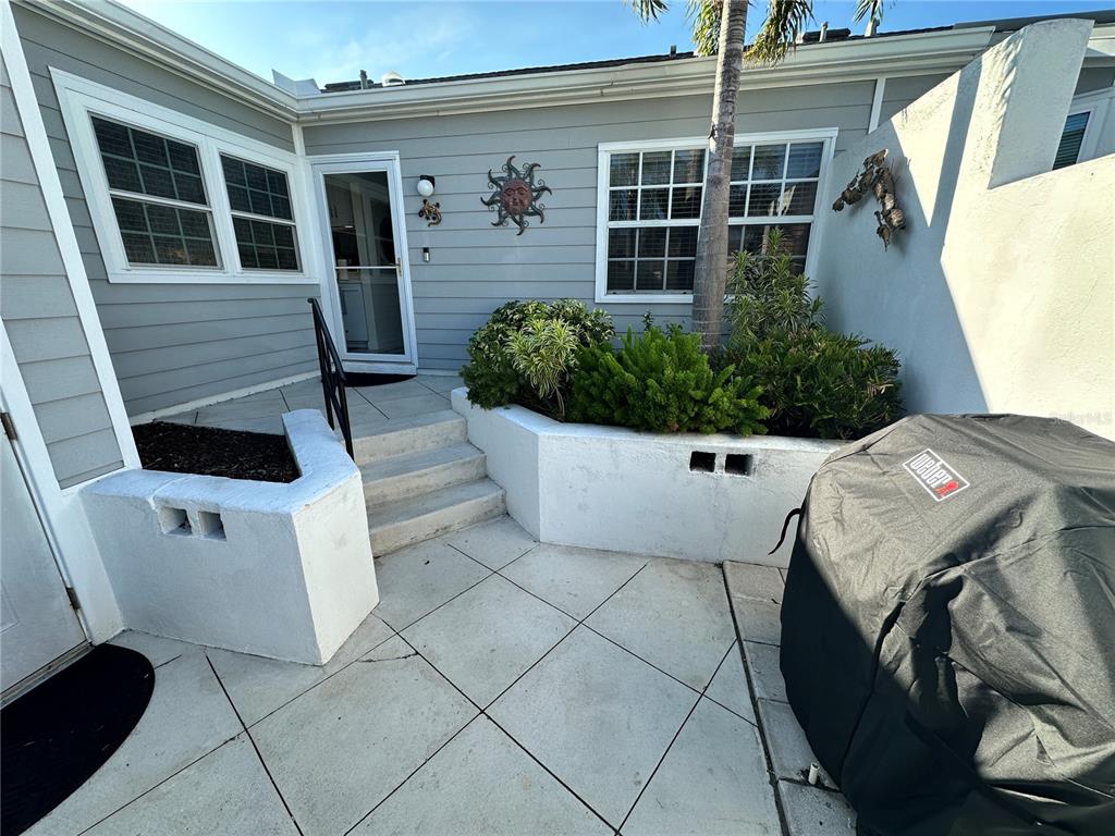 A patio area features a concrete staircase, white retaining walls, and a covered grill — 1233 SPOONBILL LANDINGS CIRCLE UNIT NA, BRADENTON, FL