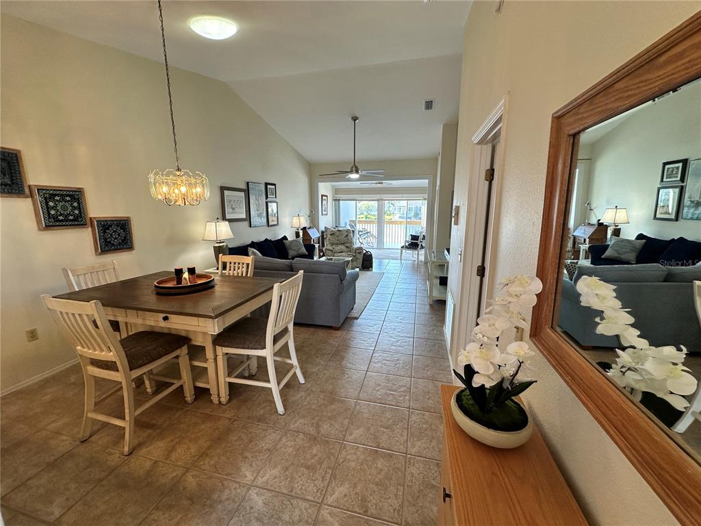 An open-concept dining and living area features tile flooring, vaulted ceilings, and a sliding door — 1233 SPOONBILL LANDINGS CIRCLE UNIT NA, BRADENTON, FL