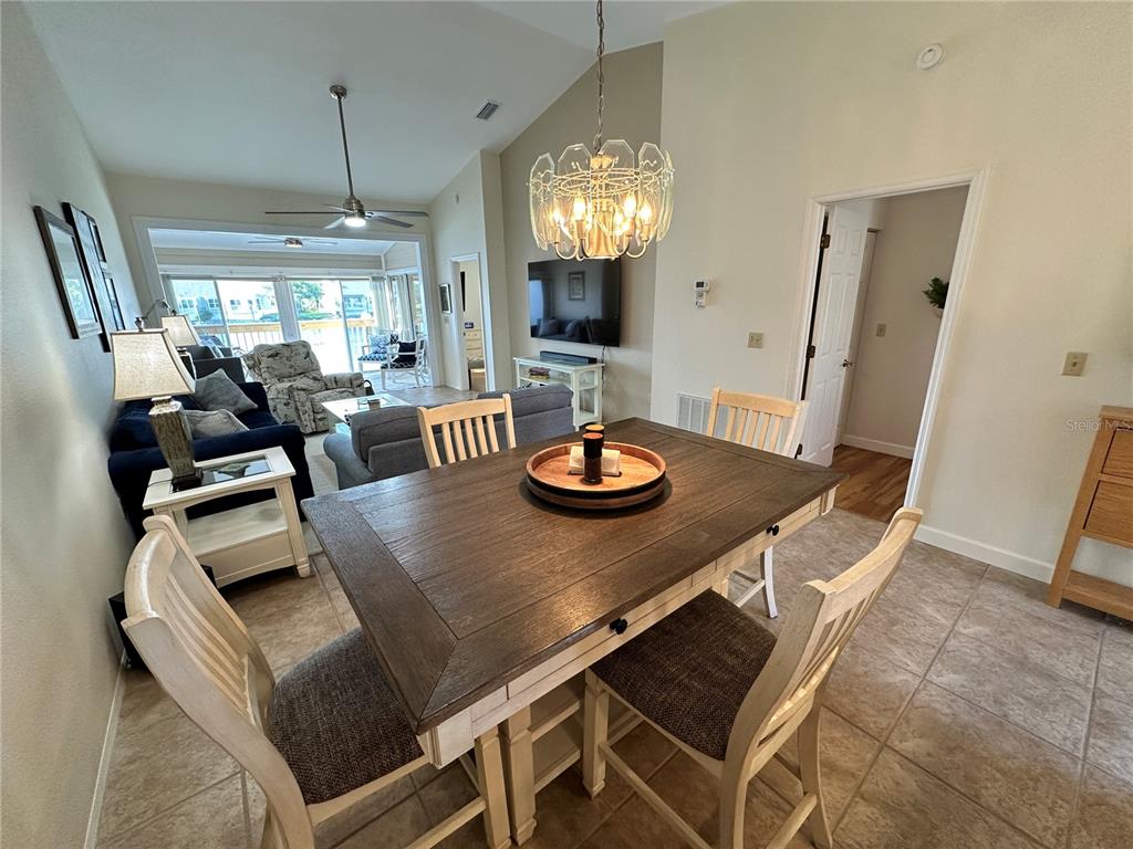 A dining area with a wooden table and chairs sits in front of a living room — 1233 SPOONBILL LANDINGS CIRCLE UNIT NA, BRADENTON, FL