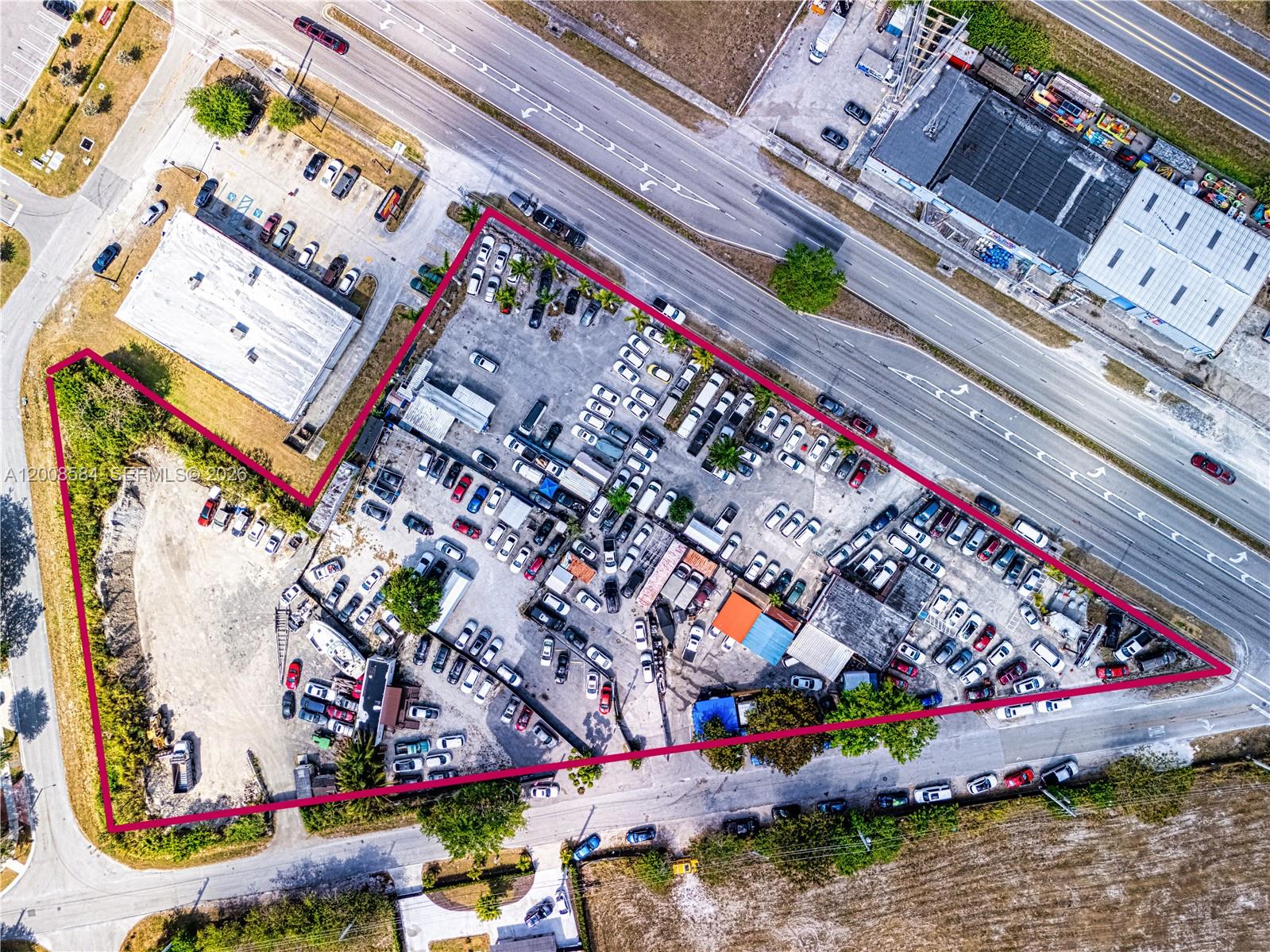 This aerial view shows a triangular commercial property filled with parked cars and buildings — 22825 S Dixie Hwy, Miami FL 33170, MIAMI, FL