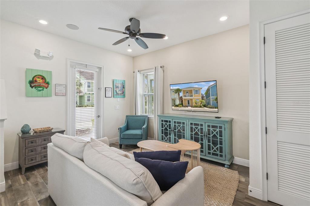 A living room features a light sofa, a teal media console, and a ceiling fan — 8081 KNEE DEEP ROAD, KISSIMMEE, FL