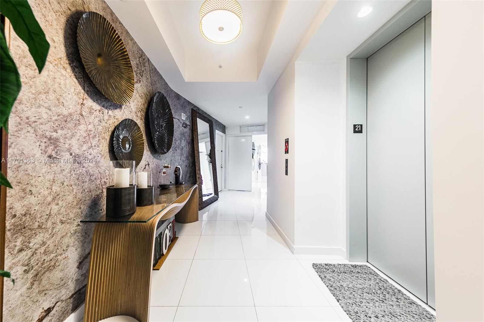 A modern hallway features a textured accent wall, a glass console table, and an elevator — 851 NE 1st Ave # 2111, Miami FL 33132, MIAMI, FL