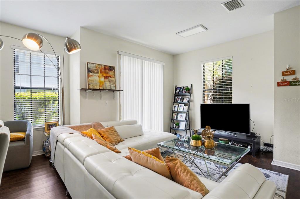 A living room with a white sectional sofa, glass coffee table, and an open kitchen — 5520 KINGLETHILL DRIVE, LITHIA, FL