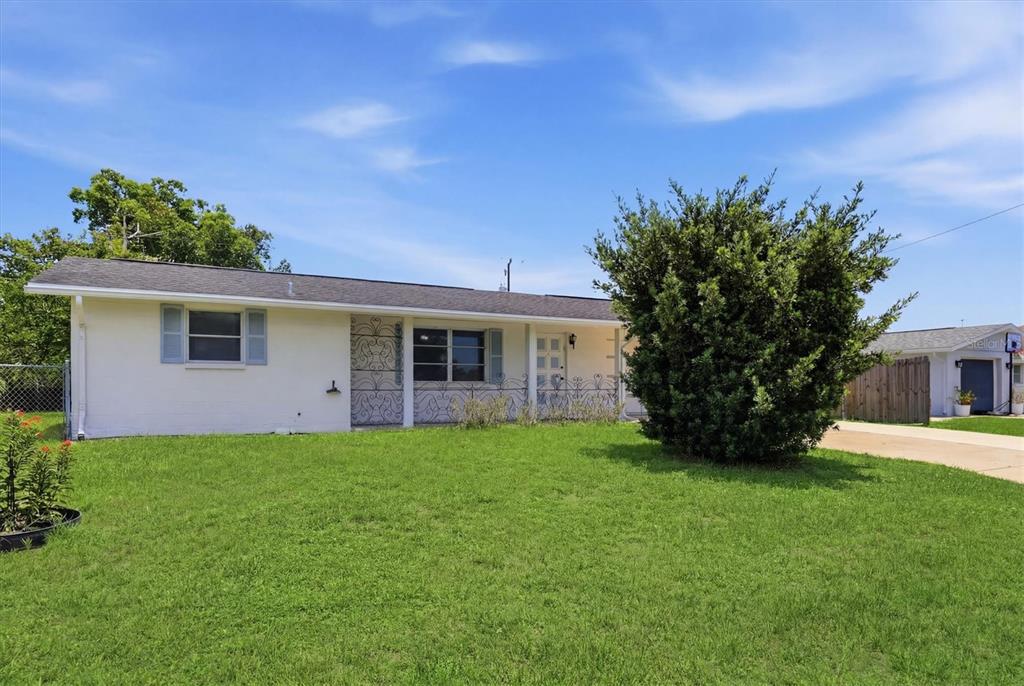 A white single-story house with a large front lawn and decorative metal porch railings — 329 SAN BENITO AVENUE, NORTH PORT, FL